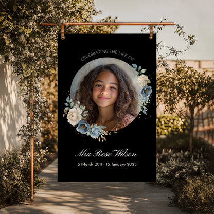 Personalized memorial welcome sign featuring a custom photo of a girl set in a circle, adorned with blue and white roses on a black background, honouring the life of Mia Rose Wilson with her date at the bottom.