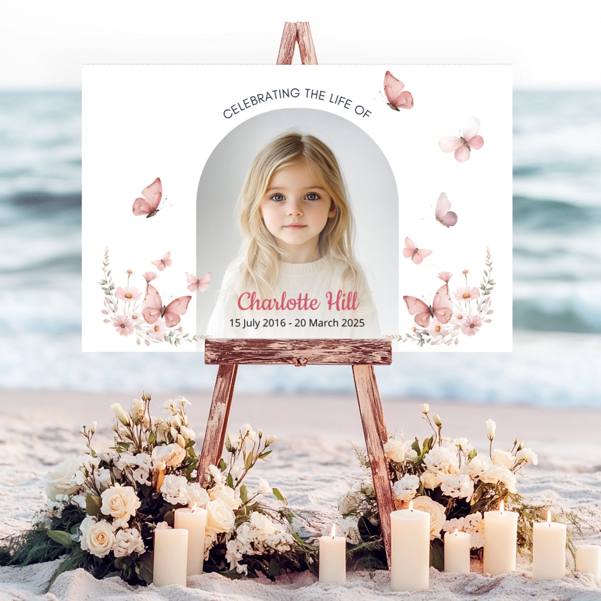 Memorial sign on a wooden easel at the beach, honouring a young girl named Charlotte Hill. Features a soft floral and butterfly design, her photo, name, and dates. Surrounded by white roses, candles, and flowers, creating a peaceful tribute.